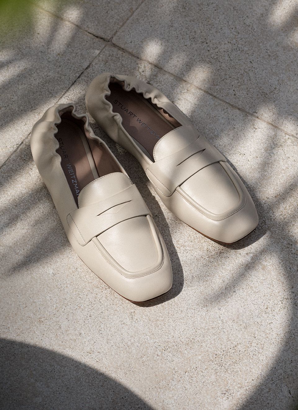 The Stuart Weitzman Bryant Loafer in Linen Leather, displayed on a stone surface 